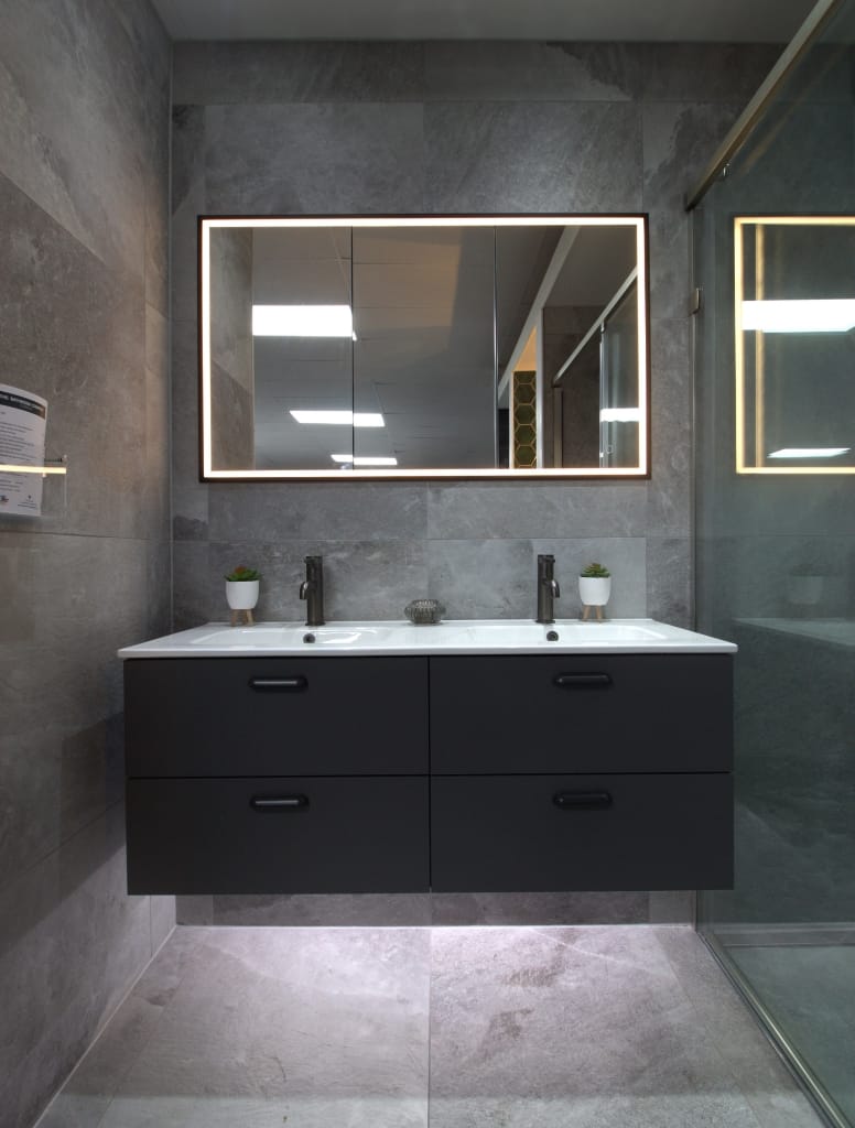 Elegant double-sink bathroom vanity in Hillington, Glasgow, with dark grey drawers, dual taps, and a large backlit mirror, surrounded by luxurious grey tile walls.