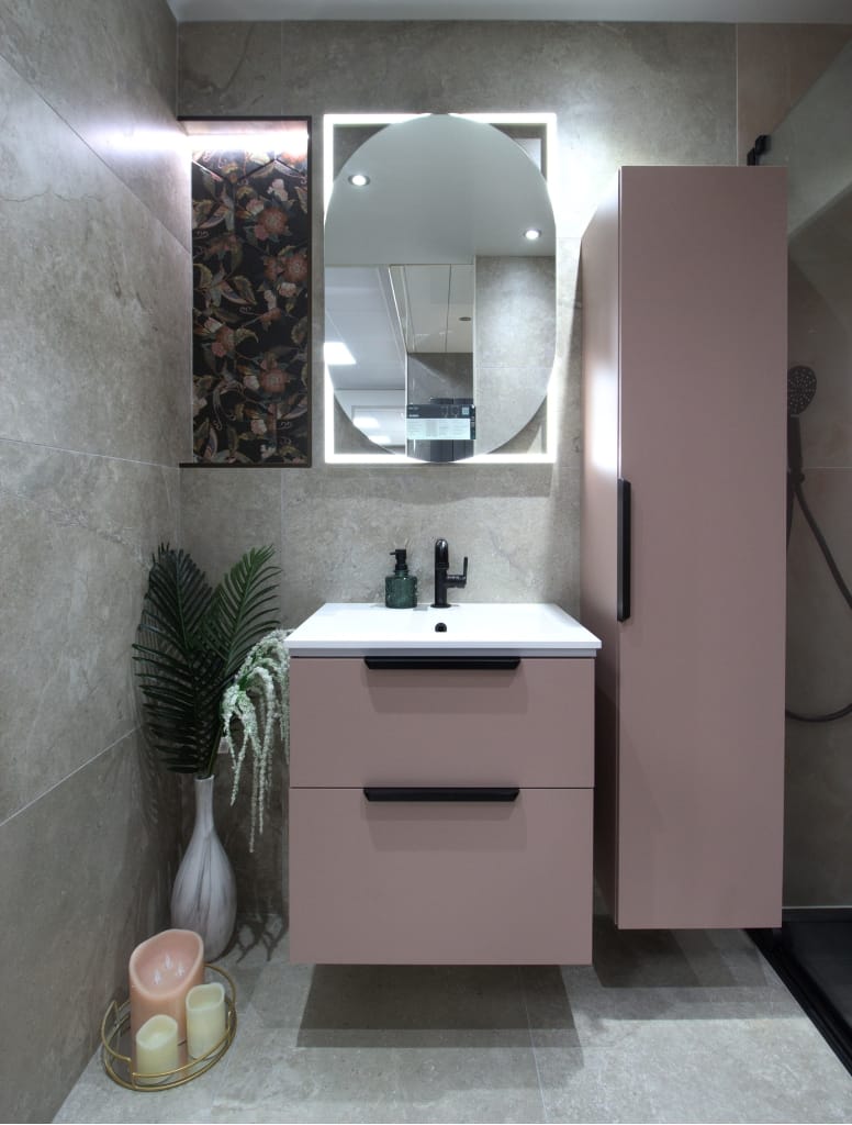 Contemporary bathroom in Glasgow with a pink floating vanity, round backlit mirror, beige tiled walls, and decorative accents, creating a soft, stylish look.